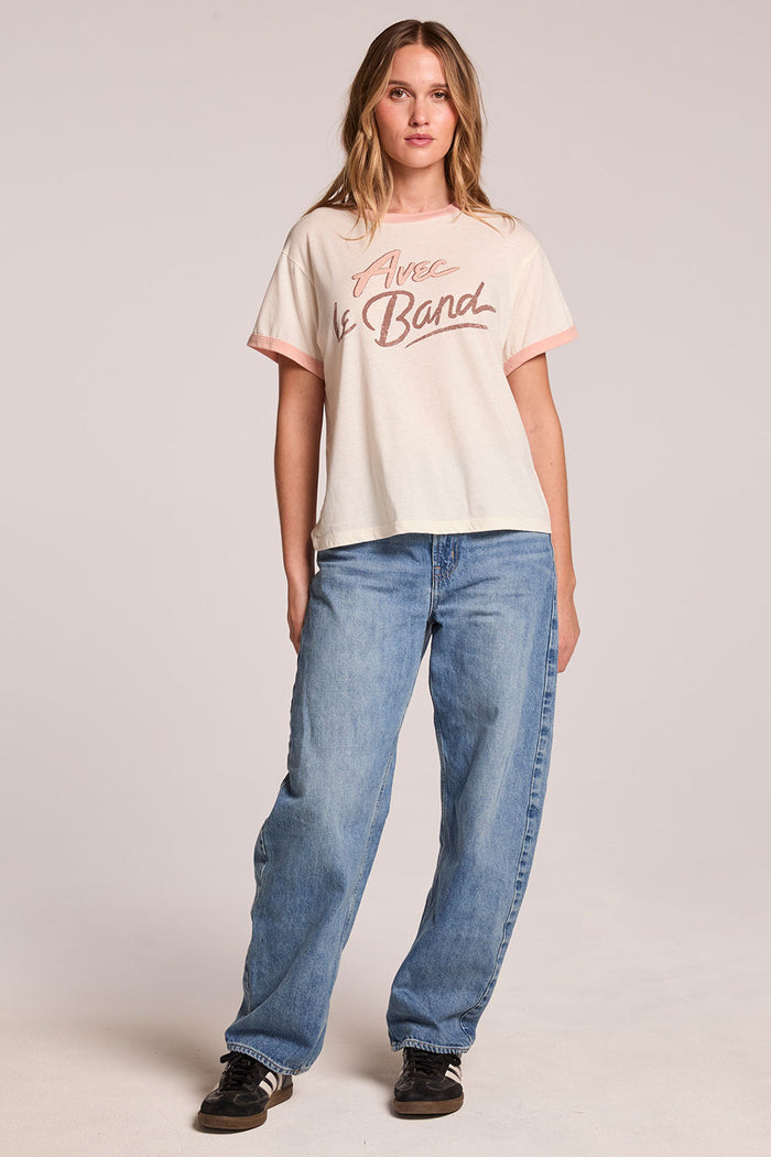Full body front view of a woman wearing the Chaser  Avec Le Band Tee and sneakers on a neutral background