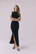 Front full body view of a woman wearing Chaser's Avenue Black Maxi Dress with a slit on a plain background