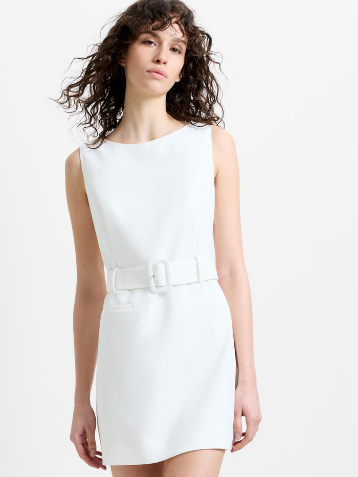 Woman wearing a white sleeveless mini dress, with a belted waist and a boat neckline