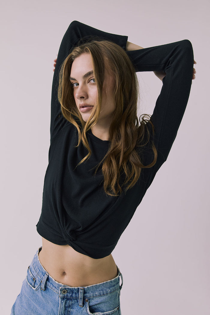 Front view of a woman wearing Chaser's Azur Black Long Sleeve top and blue jeans against a plain background