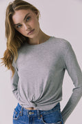 Front view of a woman wearing Chaser's Azur Heather Grey Long Sleeve top and blue jeans against a plain background