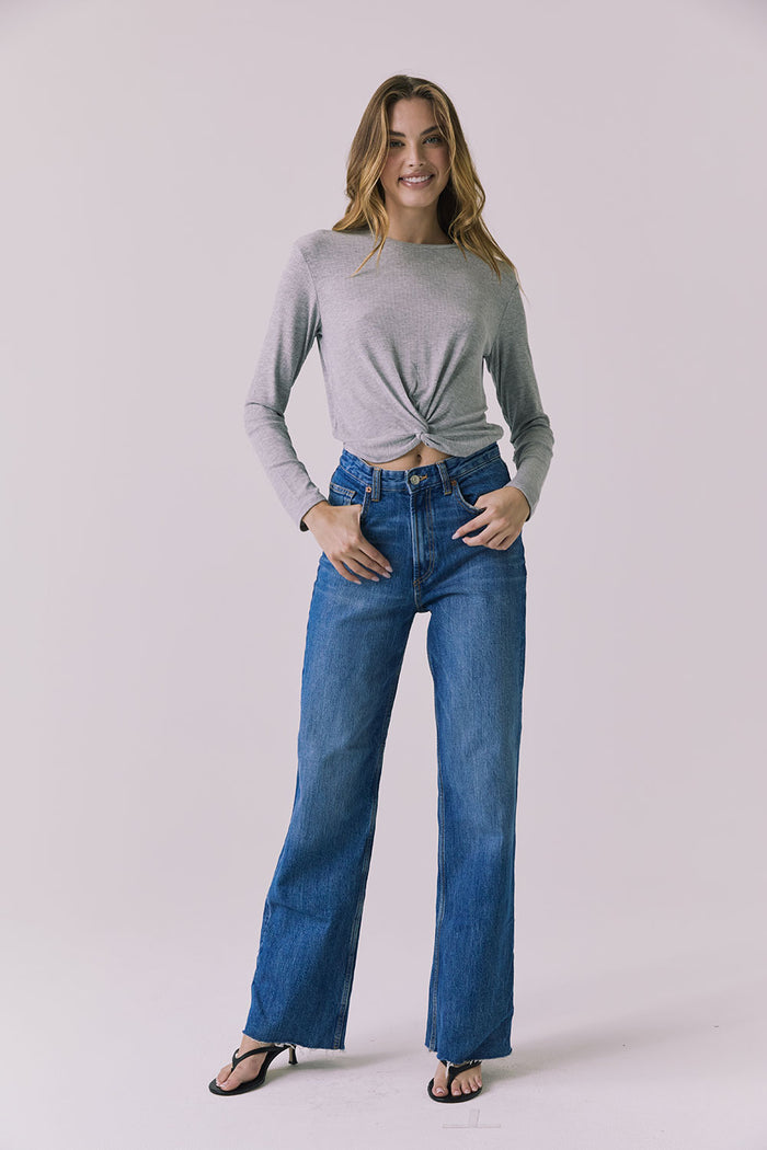 Full body front view of a woman wearing Chaser's Azur Heather Grey Long Sleeve top and blue jeans against a plain background