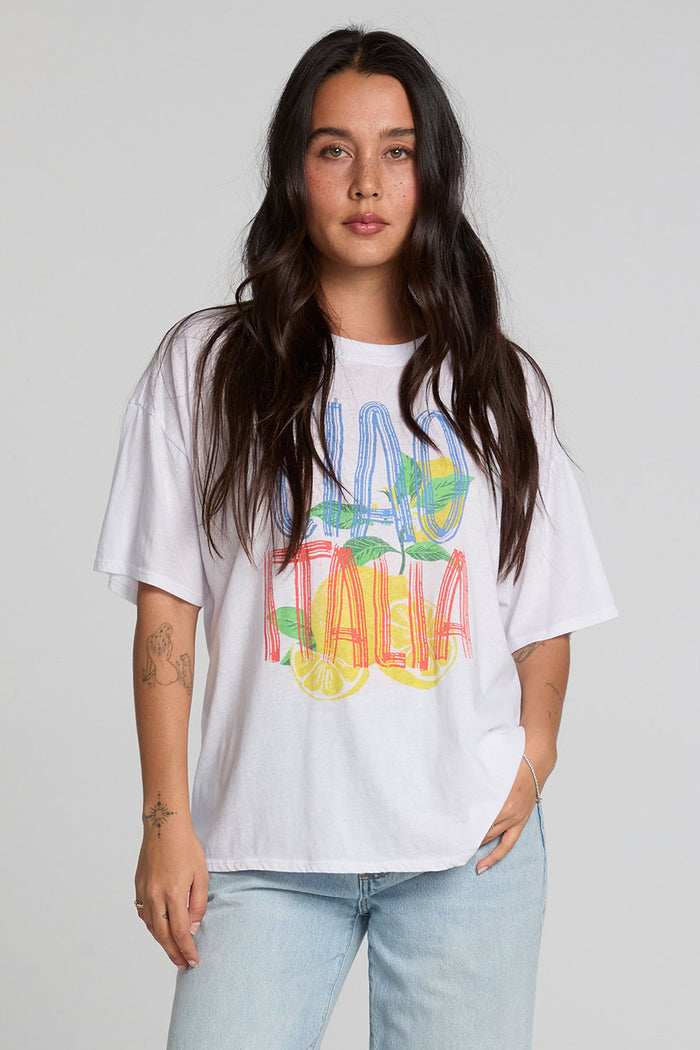 Front view of a woman wearing the Chaser Bagged Italy Tee on a neutral background with blue jeans and hand on waist