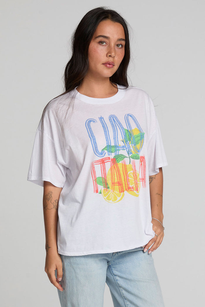 Front view of a woman wearing the Chaser Bagged Italy Tee on a neutral background with blue jeans
