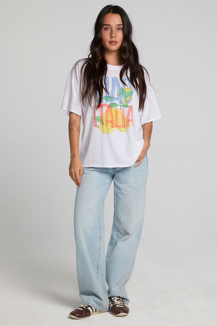 A full body front view of a woman wearing the Chaser Bagged Italy Tee on a neutral background