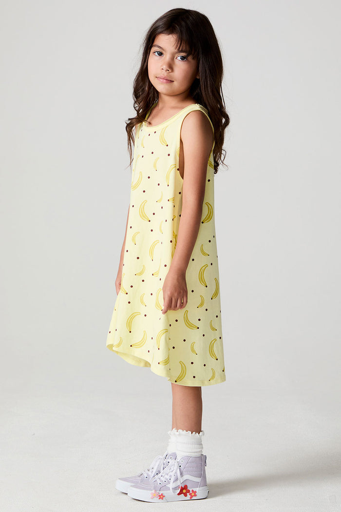 Full body side view of a girl wearing the Chaser Banana Babe Dress and sneakers on a neutral background