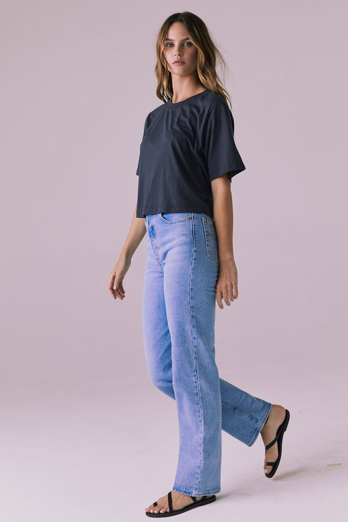 Side view of woman wearing the Chaser Beau Licorice Black Tee styled with light-wash denim for an effortless everyday look