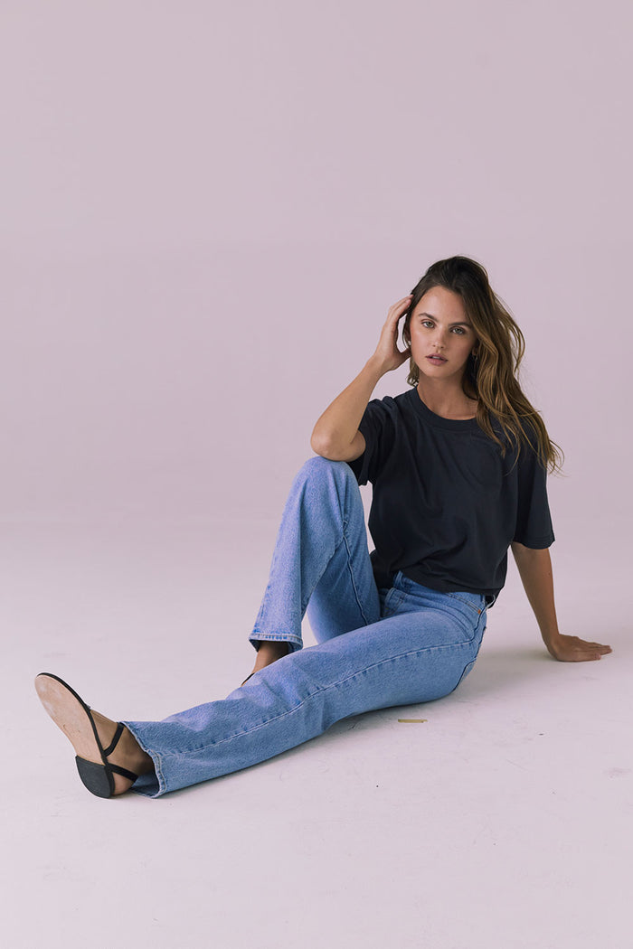 Woman sitting wearing the Chaser Beau Licorice Black Tee styled with light-wash denim for an effortless everyday look