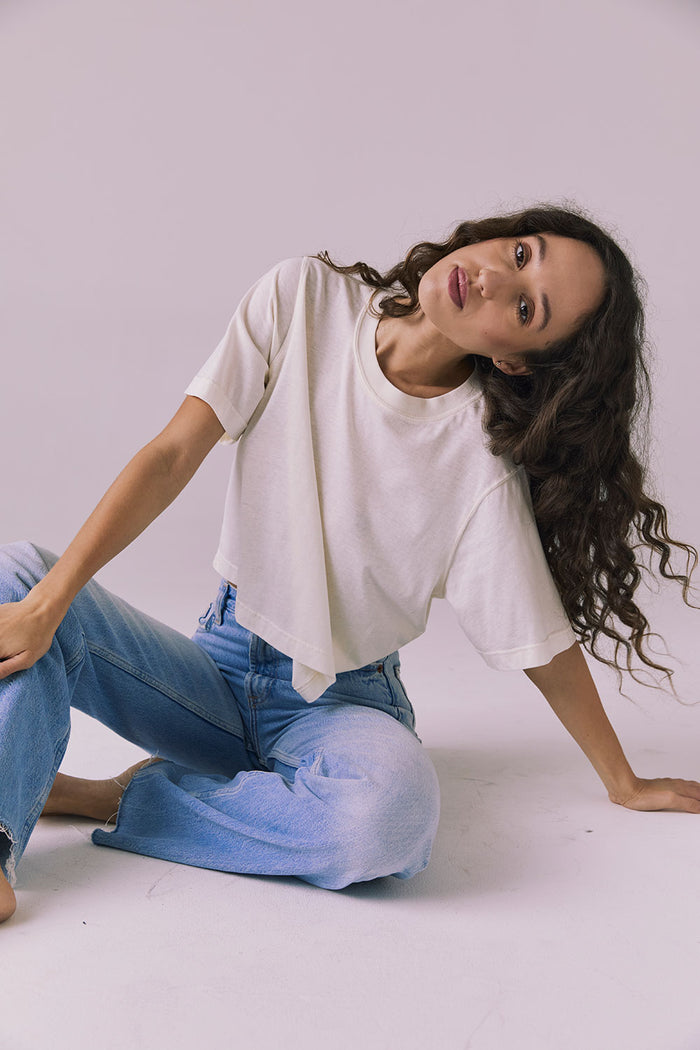 Woman sitting, wearing the Chaser Beau Starry White Tee styled with denim for a timeless, easygoing look