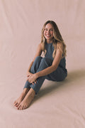 Woman sitting on a beige surface wearing Chaser's Bellow Future Grey Joggers paired with the matching Riley Tank for a coordinated loungewear look