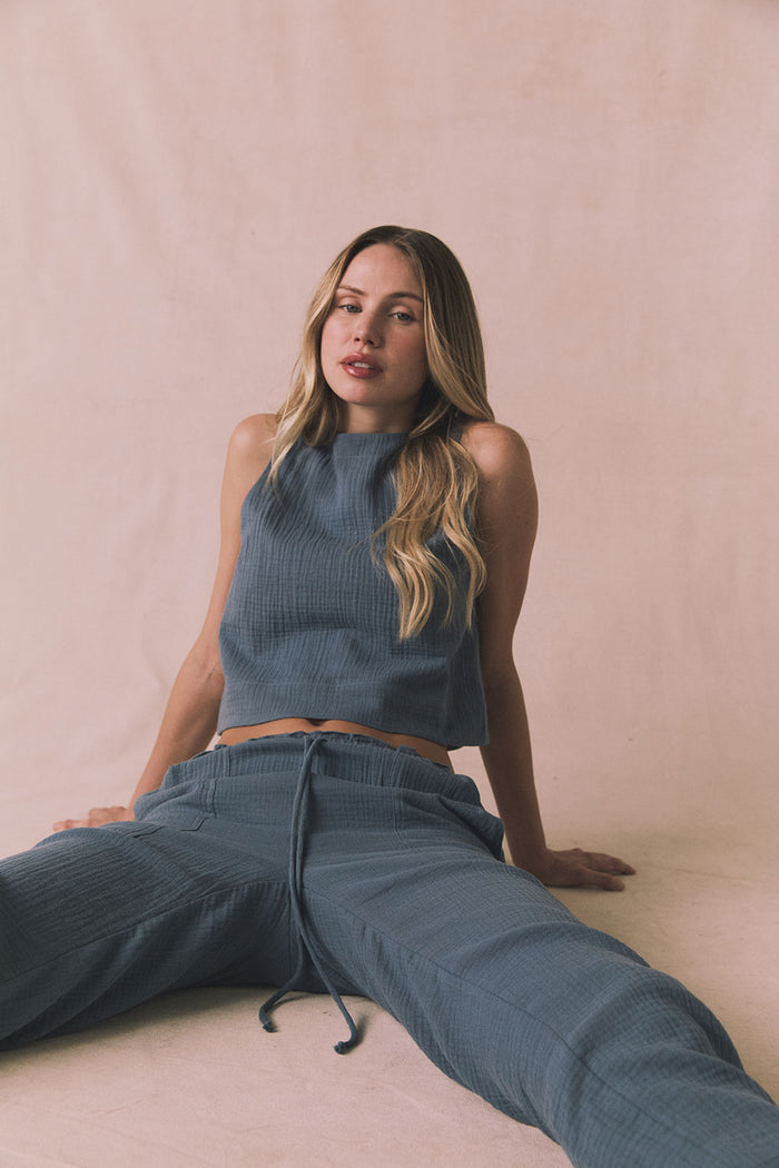 Woman sitting on a beige surface wearing Chaser's Bellow Future Grey Joggers paired with the matching Riley Tank for a coordinated loungewear look