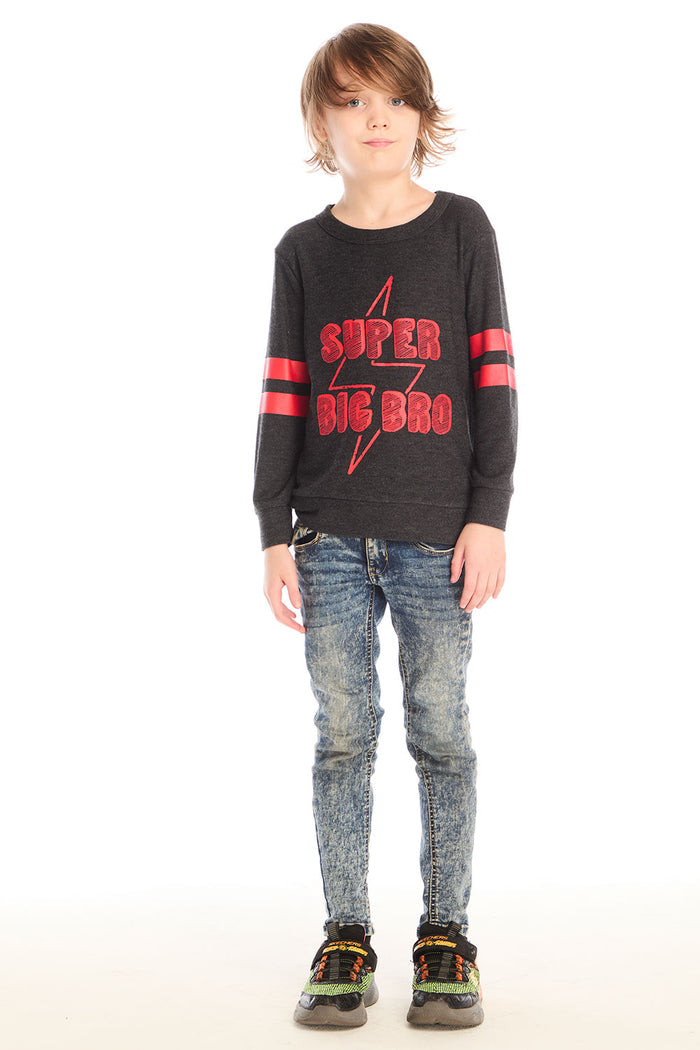 Full body view of boy wearing Chaser’s Best Brother Ever black long-sleeve shirt with red text and striped sleeves, paired with blue jeans on a white background