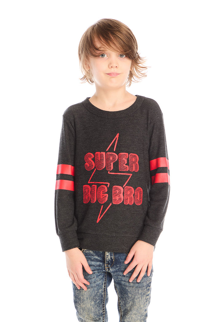 Boy wearing Chaser’s Best Brother Ever black long-sleeve shirt with red text and striped sleeves, paired with blue jeans on a white background