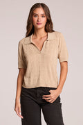A front view of a woman wearing the Chaser Bijou Khaki Polo and black pants on a neutral background