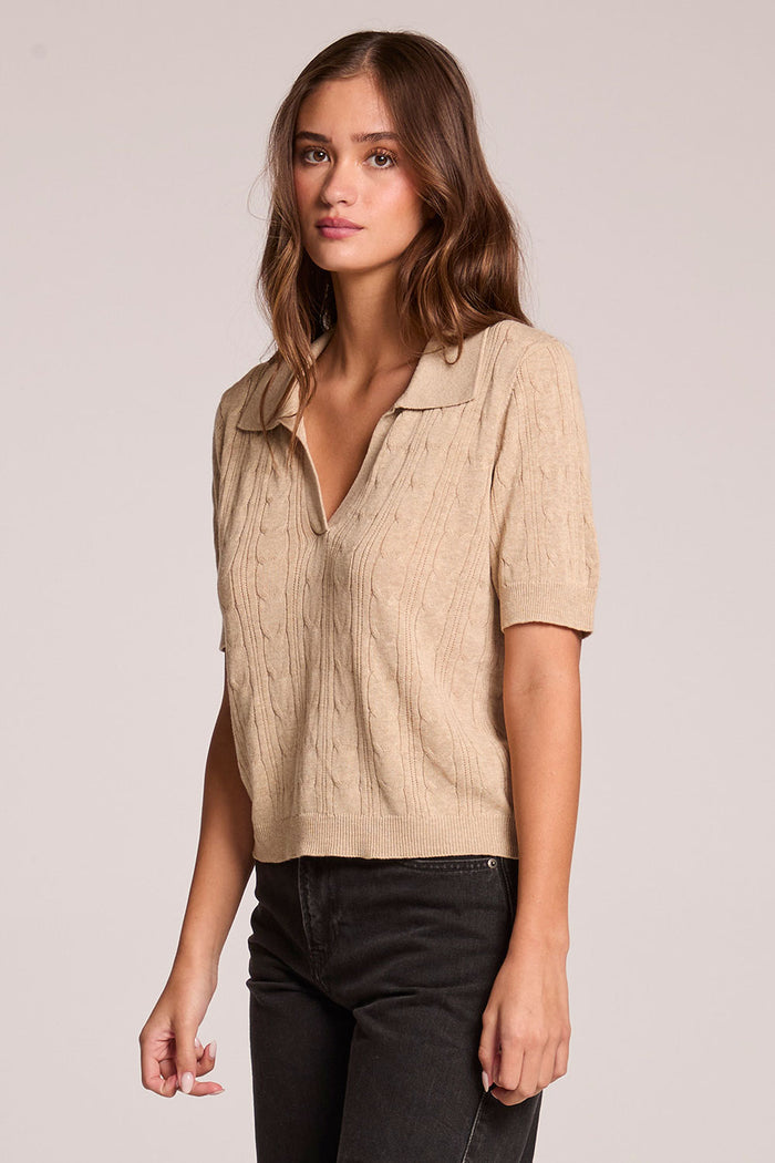 A side angle view of a woman wearing the Chaser Bijou Khaki Polo on a neutral background