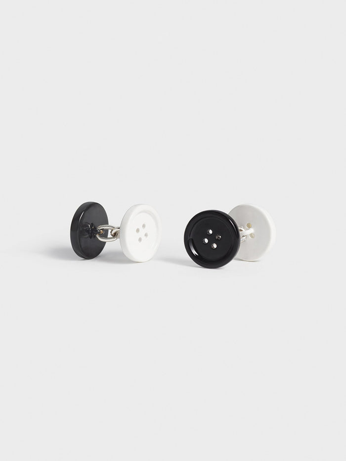 Pair of black and white button-style cufflinks on a grey background.