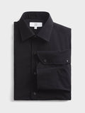 Folded black cotton dress shirt on a grey background.
