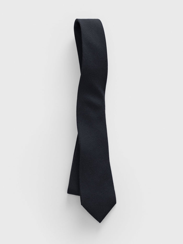 Black necktie looped and draped on a grey background.