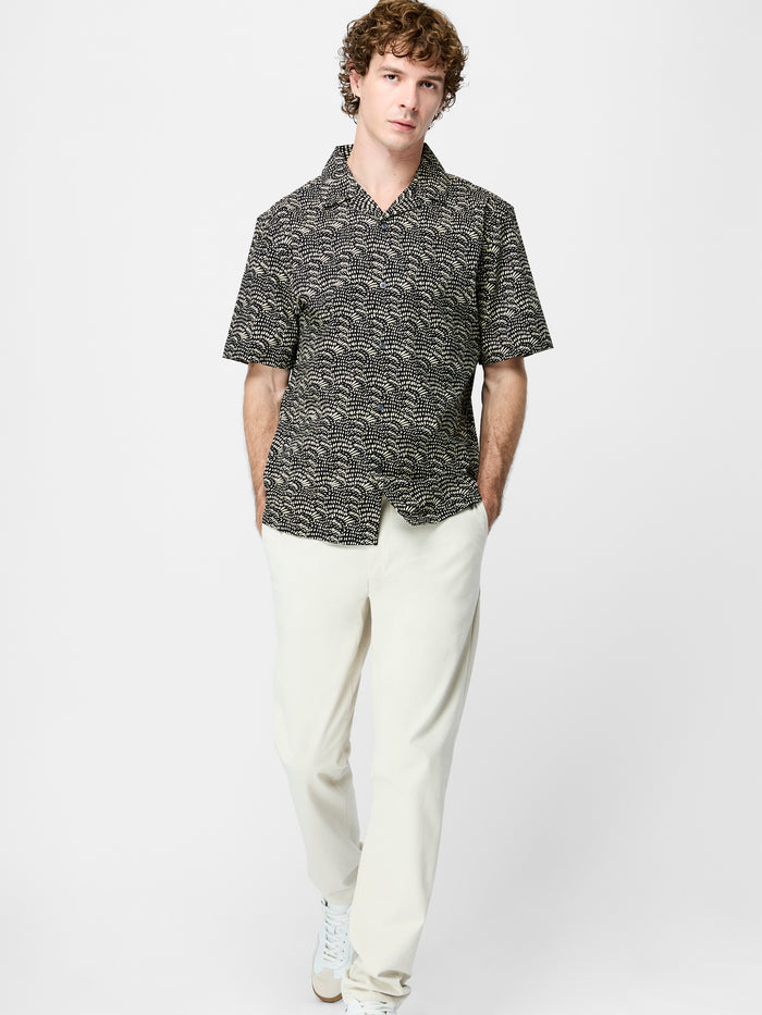 A man wearing a cotton black and cream Shirt with a geo print pattern, short sleeves, a revere collar, a button through fastening and a regular fit.