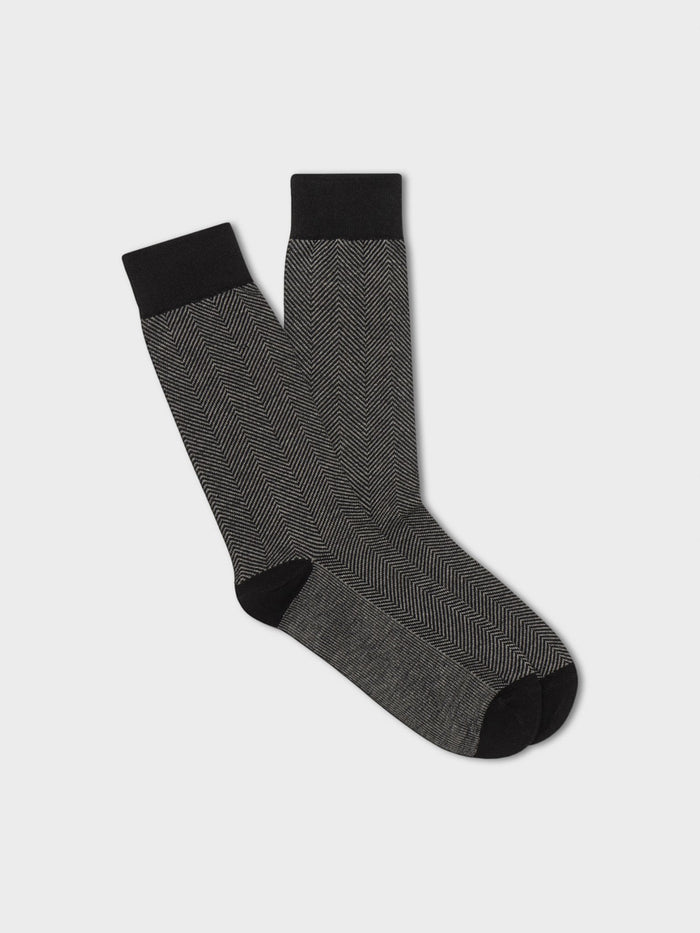 Pair of black and grey herringbone dress socks laid flat on a grey background.