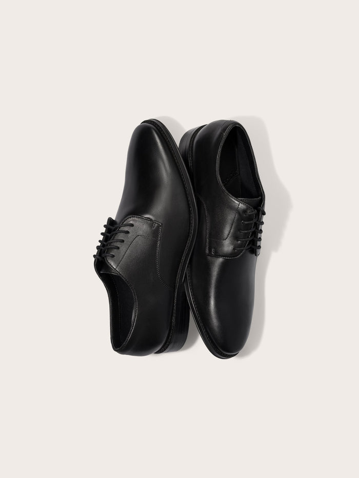 Two black leather dress shoes with laces, positioned side by side.