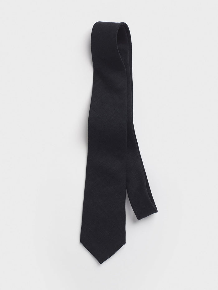 Black linen necktie looped and draped on a grey background.