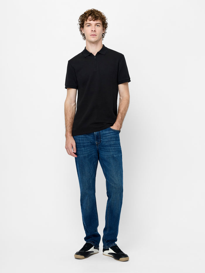 A man wearing a cotton black Polo shirt with short sleeves, a collared neckline, a metal half zip and a regular fit.