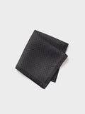 Black silk pocket square with white pindots, folded, grey background.