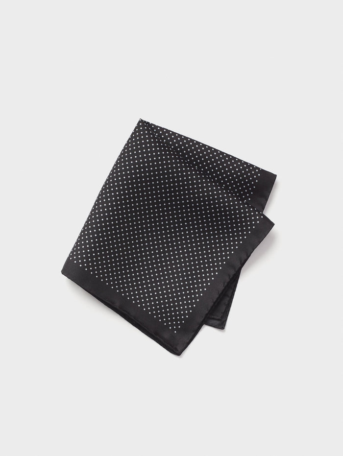 Black silk pocket square with white pindots, folded, grey background.