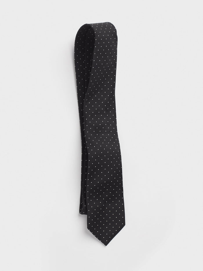 Black silk necktie with white pindots, looped on a grey background.
