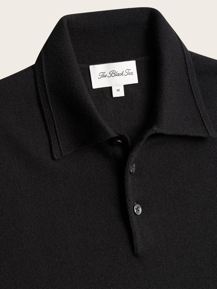 Close-up of black polo sweater collar and button placket with brand tag.
