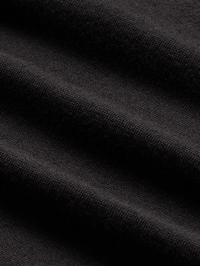 Close-up of black knit sweater fabric, draped to show texture.