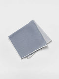 Folded quad pocket square showing a blue-grey panel with white trim, light background.