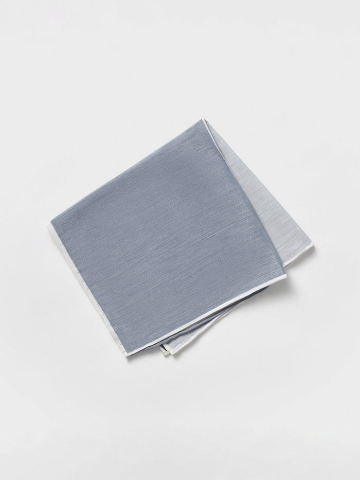 Folded quad pocket square showing a blue-grey panel with white trim, light background.