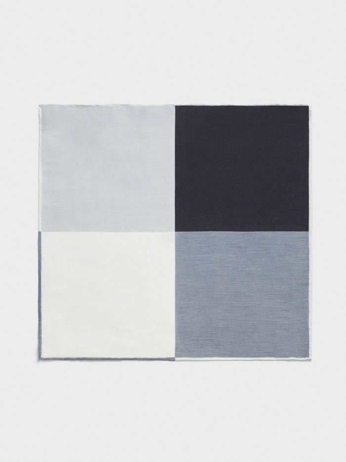 Pocket square in four color blocks: light grey, navy, white, and blue-grey, flat.