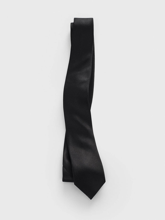 Black satin necktie looped and draped on a grey background.