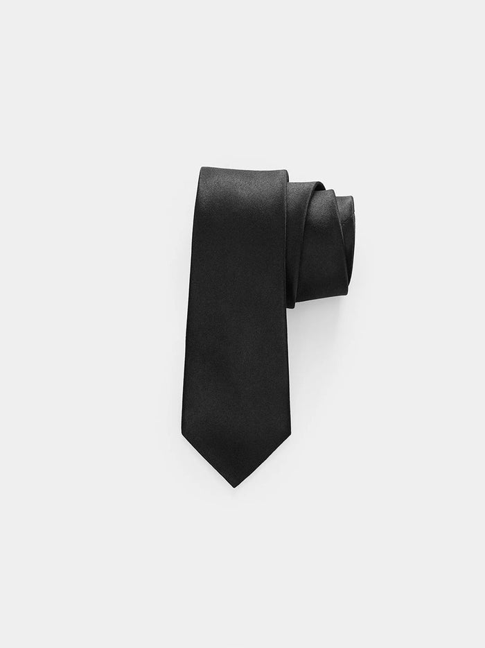 Black satin necktie rolled into a coil on a grey background.