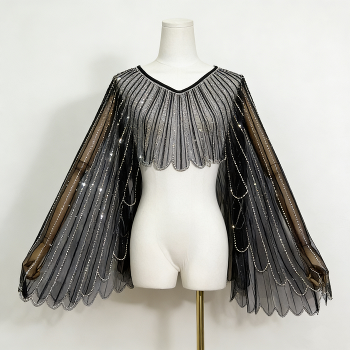 Black sheer tulle bridal cape with sequin embellishments and long flowing sleeves for modern wedding dress styling.