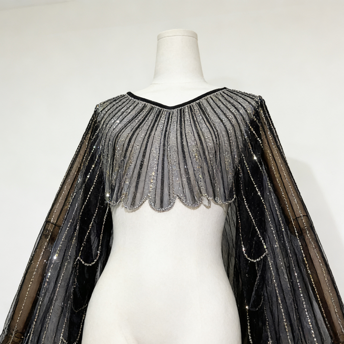 Black sheer tulle bridal cape with sequin embellishments and long flowing sleeves for modern wedding dress styling.