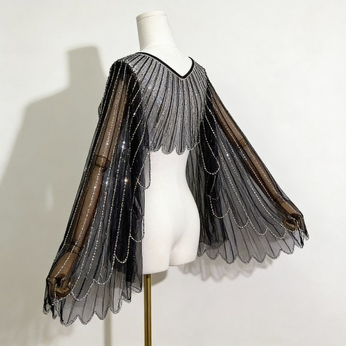 Black sheer tulle bridal cape with sequin embellishments and long flowing sleeves for modern wedding dress styling.