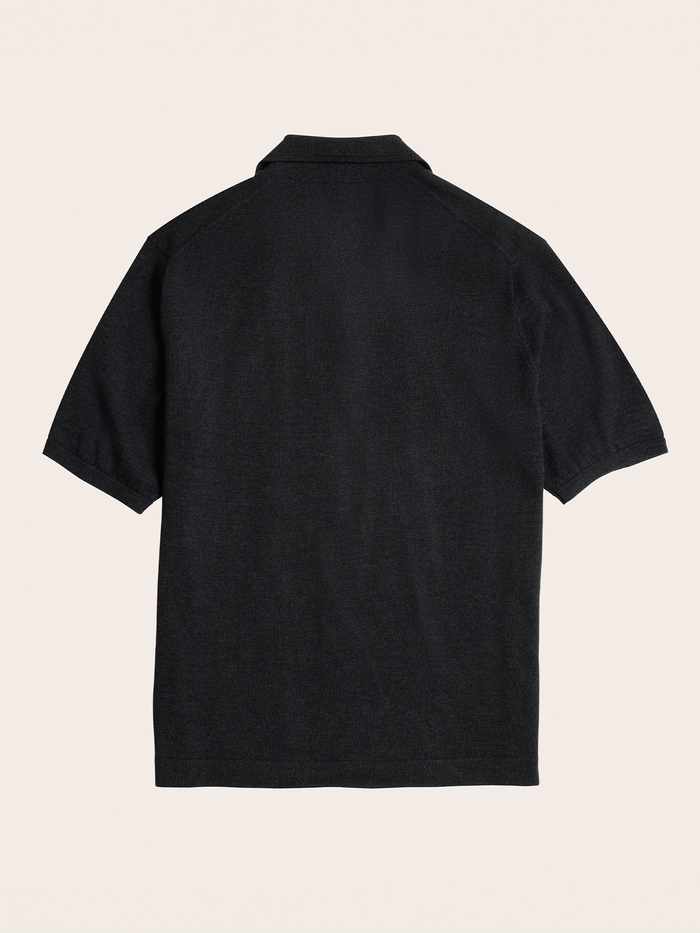 Black short-sleeve sweater polo, flat lay, back view, cream background.