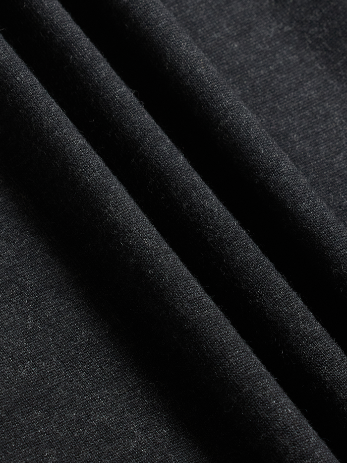 Close-up of black knit fabric, draped to show ribbed texture.