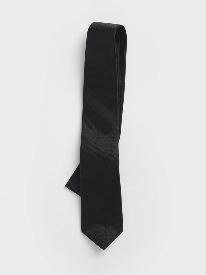 Black silk twill necktie loosely rolled with the blade pointing down on a white background