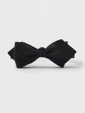Black silk twill diamond-point bow tie, tied, on a grey background.