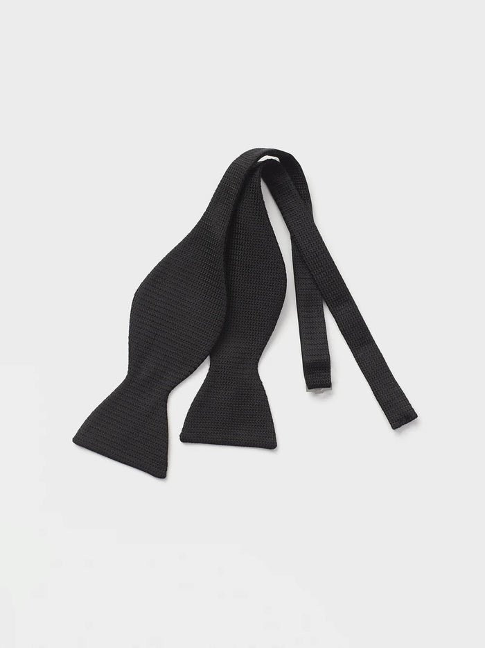 Untied black textured silk bow tie laid flat as a self-tie strip on a white background.