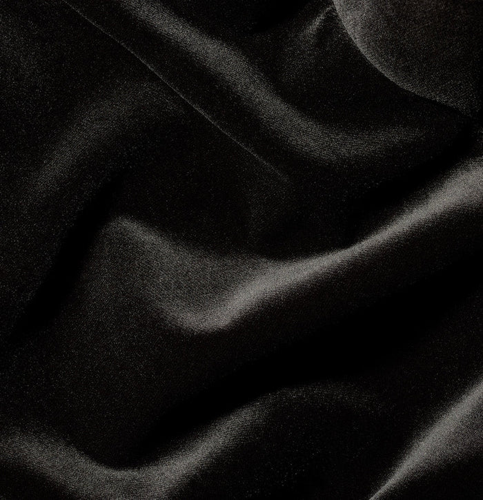 Close-up of black velvet fabric, draped to show sheen and folds.