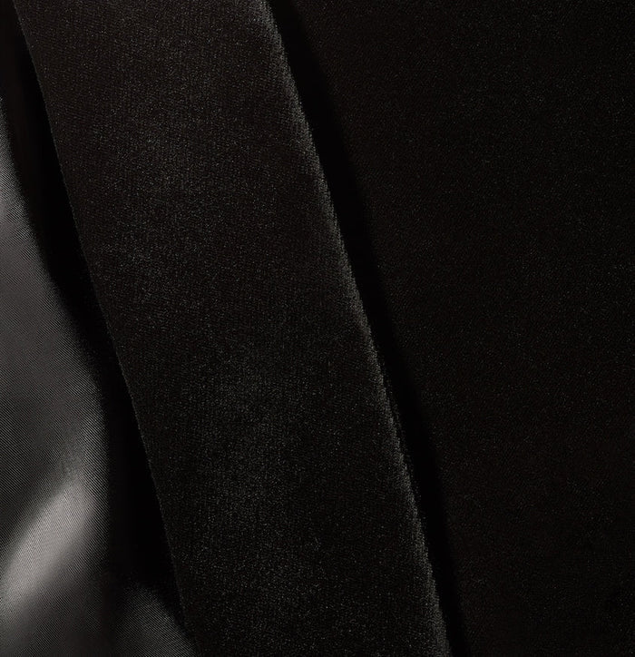 Close-up of black velvet fabric with diagonal fold, subtle sheen visible.