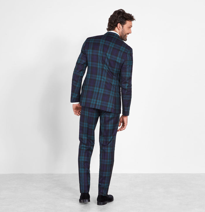 Man in a black watch tartan tuxedo, back view, full length, white background.