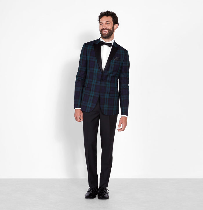 Man in a black and green tartan tuxedo jacket, full-length front view, white background.