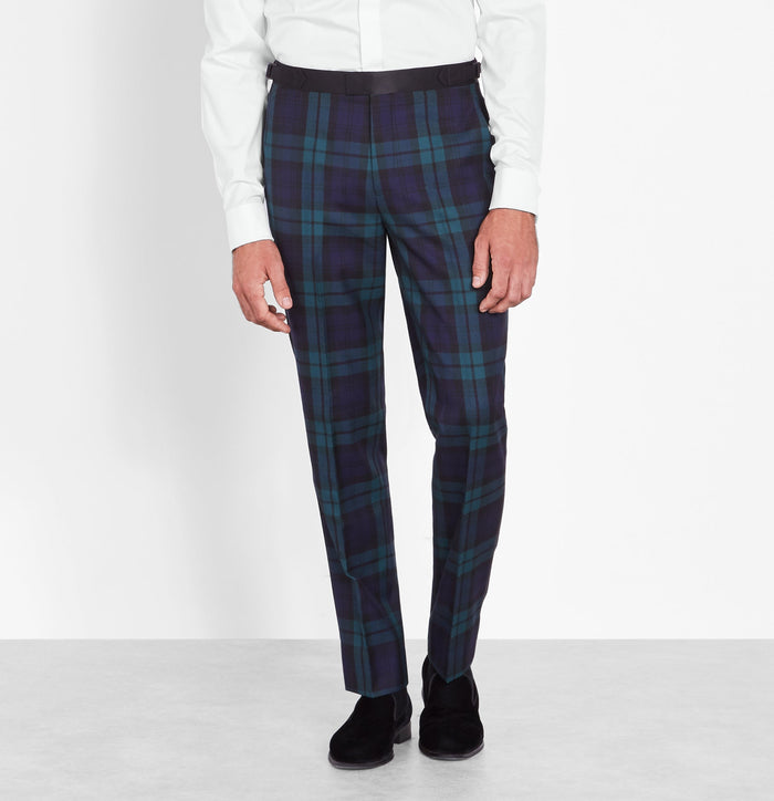 Close-up of black watch tartan tuxedo trousers, white shirt visible above.